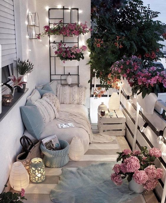 outdoor balcony, set up with candles, a loveseat, and a variety of flowers. overlooking one of blossomcrown's streets, and with an overhead shutter that can be pulled over in case of rain. balcony